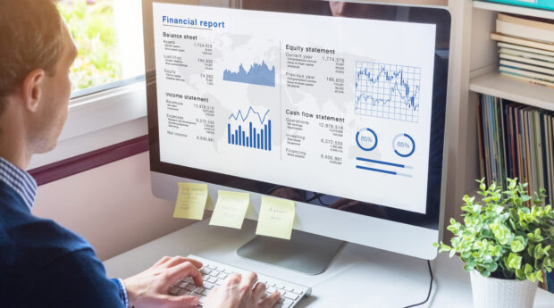 man looking at a computer screen showing financial inforation