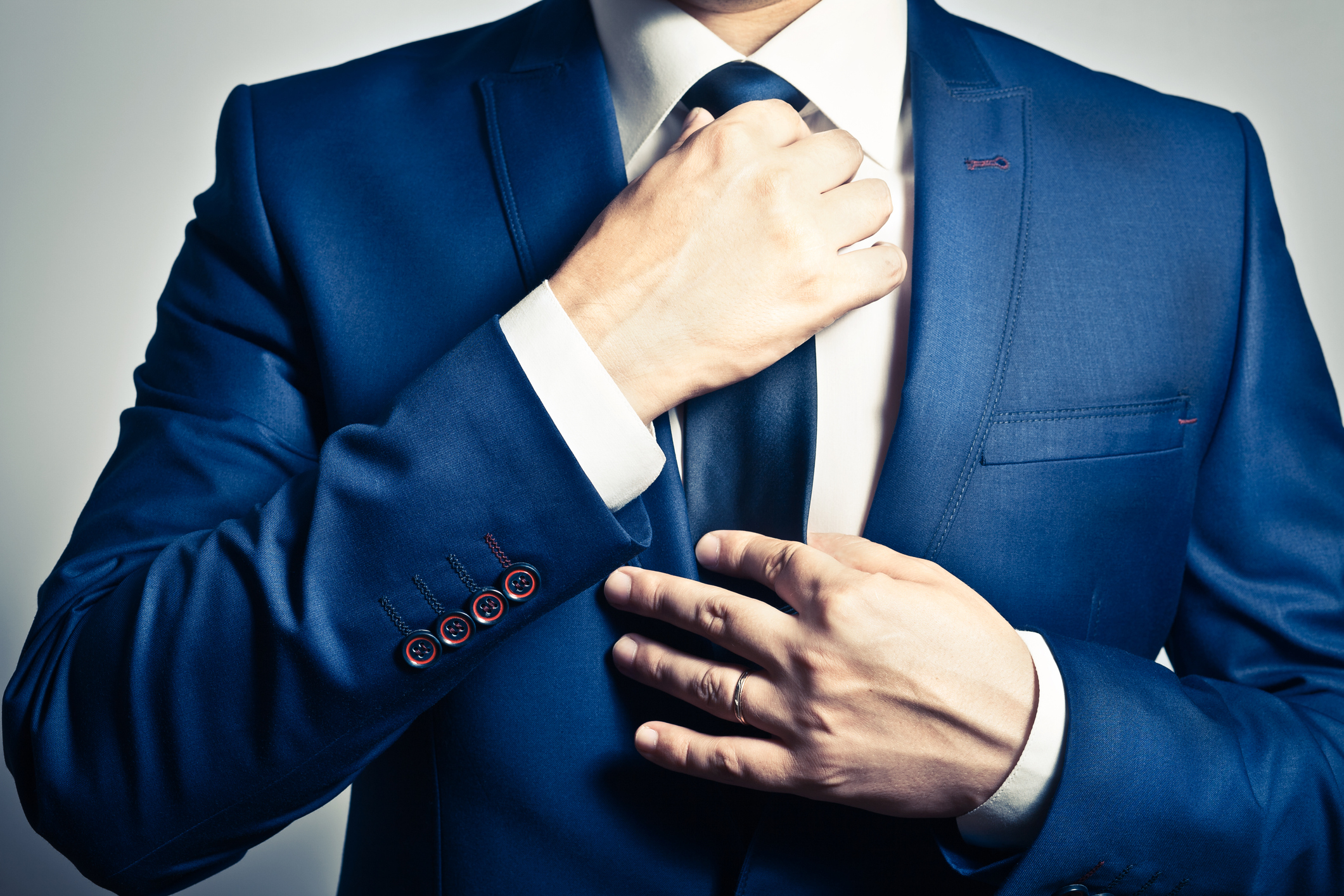 headless businessman in blue suit adjusting tie